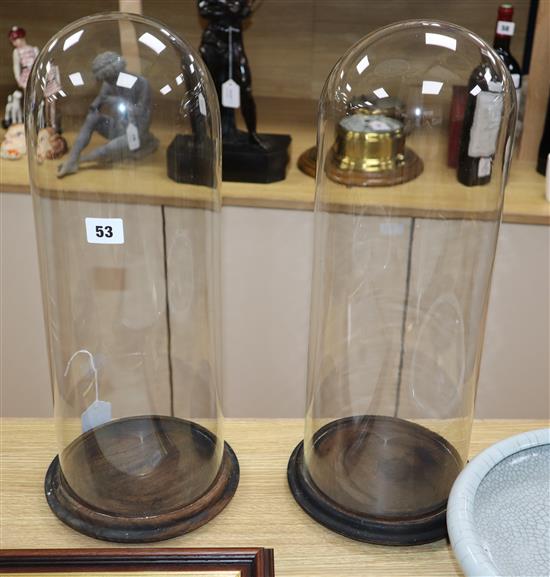 A pair of glass domes on wood stands height 48cm